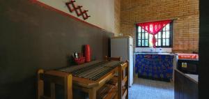 Una cocina con una mesa de madera y un refrigerador. en Tahoma Chale Rustico côr Café e vermelho Prumirim Paraiso, en Ubatuba