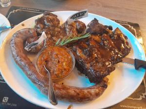 a plate of food with a sausage and meat at The PHOMOLONG GUEST HOUSE in Roodepoort