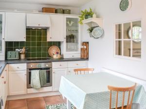 a kitchen with white cabinets and a table with chairs at Cooper's Cottage in Louth