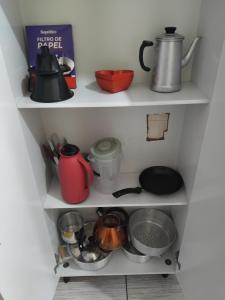 アグアス・デ・リンドイアにあるApartamento da mel 2のキッチンにある鍋やフライパンが置かれた2つの白い棚