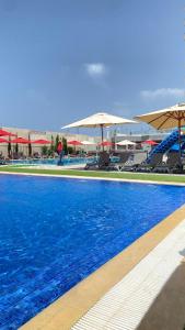 ein großer Swimmingpool mit blauem Wasser und Sonnenschirmen in der Unterkunft Hotel Falcon Thalassa Resort & SPA in Aïn El Turk