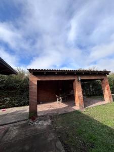 a brick pavillion with a table and a chair in it at Casaquinta zona Aeropuerto Sauce Viejo in Santa Fe