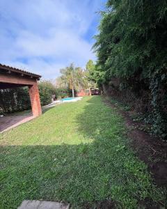 a grassy yard with a swimming pool in the distance at Casaquinta zona aeropuerto Sauce Viejo 