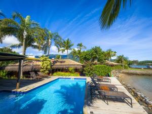 a pool at a resort with chairs and trees at Pousada Vila das Velas in Ilhabela