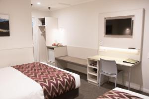 a bedroom with a bed and a desk with a computer at Wanaka Hotel in Wanaka