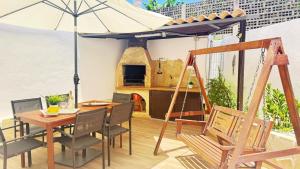 アデへにあるBeach Paradise Apartmentのテーブルと椅子と傘のあるパティオ