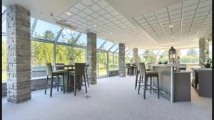 une grande pièce avec des tables, des chaises et des fenêtres dans l'établissement Lakefront Wellness Estate - Pool, Sauna and Hot Tub, à Lac-Simon