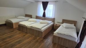 two beds in a room with a window at White Apartment Peștera Urșilor in Chişcău