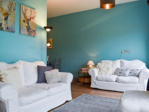 two white couches in a living room with blue walls at Ty Ffair Mai Annexe in Llangwm-isaf
