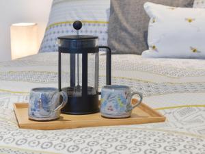 a tray with three mugs on a bed at Ty Ffair Mai Annexe in Llangwm-isaf