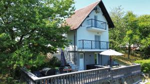 a white house with a fence and an umbrella at Tri Tresnje & Three Cherries in Grabovnica