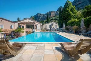 a swimming pool with two chairs and a house at Hôtel La Bonne Auberge in Moustiers-Sainte-Marie