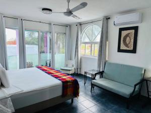 a bedroom with a bed and a chair and windows at The Quetzal in Cancún