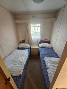 a small room with two beds and a window at Beckys Holiday Van in Ingoldmells