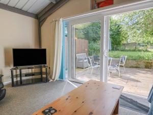 ein Wohnzimmer mit einem TV und einer Glasschiebetür in der Unterkunft Brookfield Lodge in Burstock
