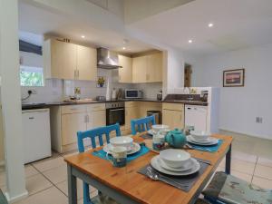 eine Küche mit einem Holztisch und blauen Stühlen in der Unterkunft Brookfield Lodge in Burstock