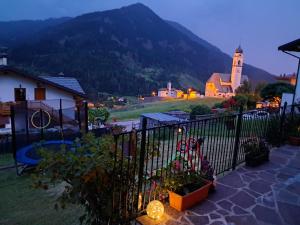 a building with a fence and a church and a mountain at Casa Anelis in Bedollo