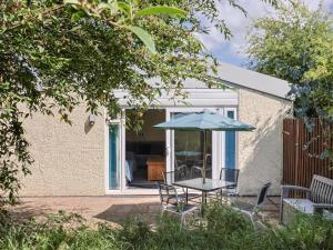 eine Terrasse mit Tisch und Sonnenschirm in der Unterkunft Brookfield Lodge in Burstock