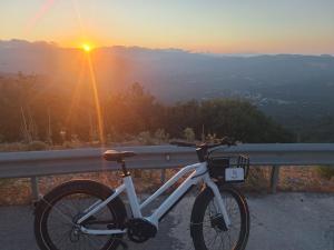 a bike parked next to a railing with the sunset at Kandania Paradise in Kántanos