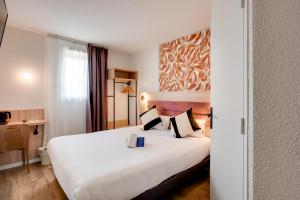 Una habitación de hotel con una gran cama blanca y una ventana. en Sure Hotel by Best Western Valence Nord, en Bourg-lès-Valence