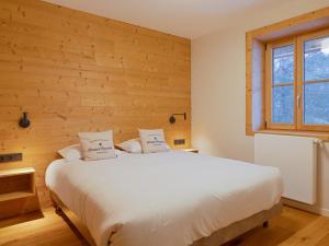 - une chambre avec un lit blanc et un mur en bois dans l'établissement Chalet familial rénové au pied des pistes - FR-1-808-22, au Monêtier-les-Bains