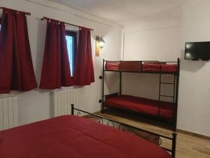 a bedroom with two bunk beds and red curtains at Locanda Sarel, intera casa vacanza 4 camere 5 bagni 14 posti letto in Pescasseroli