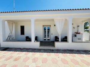 a white house with white walls and a patio at B&B Del Popolo in Torre Chianca