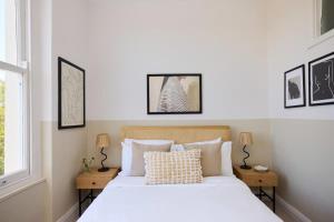 a bedroom with a bed with white sheets and pillows at The Camden Hideout - Modish and Bright 2BDR Flat in London