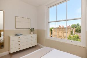a white bedroom with a dresser and a window at The Camden Hideout - Modish and Bright 2BDR Flat in London