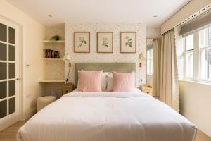Un dormitorio con una gran cama blanca con almohadas rosas. en The Chelsea Abode - 4BDR Home with Terrace, en Londres