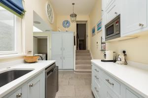 Una cocina con gabinetes blancos y un fregadero. en The Chelsea Abode - 4BDR Home with Terrace, en Londres