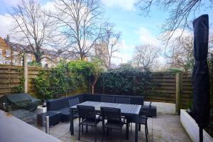 een terras met een tafel, stoelen en een hek bij The Clapham Crib - Spacious 4BDR House with Patio in Londen
