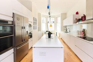 een keuken met witte kasten en roestvrijstalen apparaten bij The Clapham Crib - Spacious 4BDR House with Patio in Londen