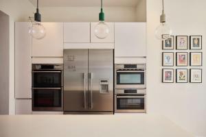 een keuken met roestvrijstalen apparaten en schilderijen aan de muur bij The Clapham Crib - Spacious 4BDR House with Patio in Londen