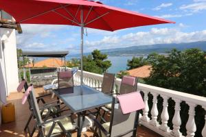 stół i krzesła z czerwonym parasolem na balkonie w obiekcie Apartment in Silo - Insel Krk 13554 w mieście Šilo