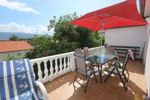 stół i krzesła na balkonie z czerwonym parasolem w obiekcie Apartment in Silo - Insel Krk 13554 w mieście Šilo