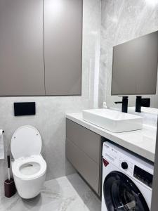 a bathroom with a toilet and a sink and a washing machine at Апартаменты по суточно in Zhezdi +13 photos
