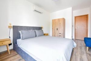 a bedroom with a large white bed and a blue chair at New Building, Free Parking Perfect For Families in Sofia