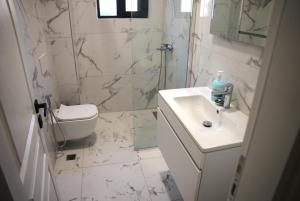 a white bathroom with a sink and a toilet at Duo Lux Golem Apartment in Golem +12 photos