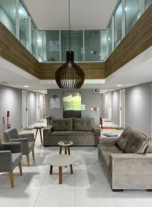 una sala de estar con sofás, mesas y una lámpara de araña. en Flat aconchegante praia do cupe, en Ipojuca