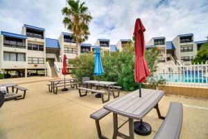 a group of picnic tables with umbrellas in front of a building at Swim, Fish and Suntan Cozy Corpus Christi Retreat in Corpus Christi