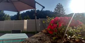 a garden with a table and an umbrella and flowers at Ferienwohnung Döll in Gernsbach