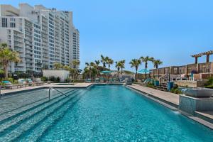 einen Pool in einem Resort mit Palmen und Gebäuden in der Unterkunft Another Day in Paradise Beachfront Bliss Remodeled Luxury Sandestin® Escape in Destin