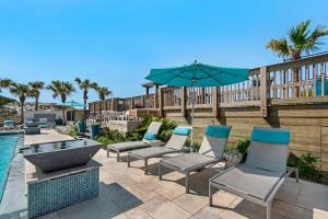 eine Terrasse mit Stühlen und einem Sonnenschirm neben einem Pool in der Unterkunft Another Day in Paradise Beachfront Bliss Remodeled Luxury Sandestin® Escape in Destin