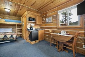 Dormitorio en cabaña de madera con escritorio y cama en Black Hills Trailside Park Resort, en Hill City