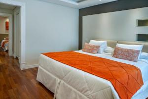 a bedroom with a large bed with an orange blanket at Hotel Serra da Estrela in Campos do Jordão