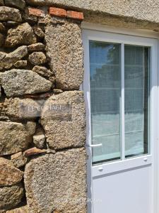 eine weiße Tür an einer Steinmauer mit einem Fenster in der Unterkunft Cottage Authentique avec Mezzanine proche du Puy duFou in LʼÉpaux