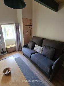 ein Wohnzimmer mit einem blauen Sofa und einem Fenster in der Unterkunft Cottage Authentique avec Mezzanine proche du Puy duFou in LʼÉpaux