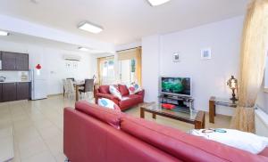 a living room with a red couch and a tv at Villa Leoforos Dyo, Modern 3Bdr Protaras Villa With Pool, In The Centre Of Protaras in Protaras