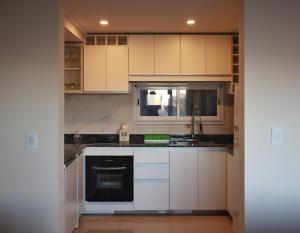 a kitchen with white cabinets and a black dishwasher at Tandil Centro vistas in Tandil +14 photos
